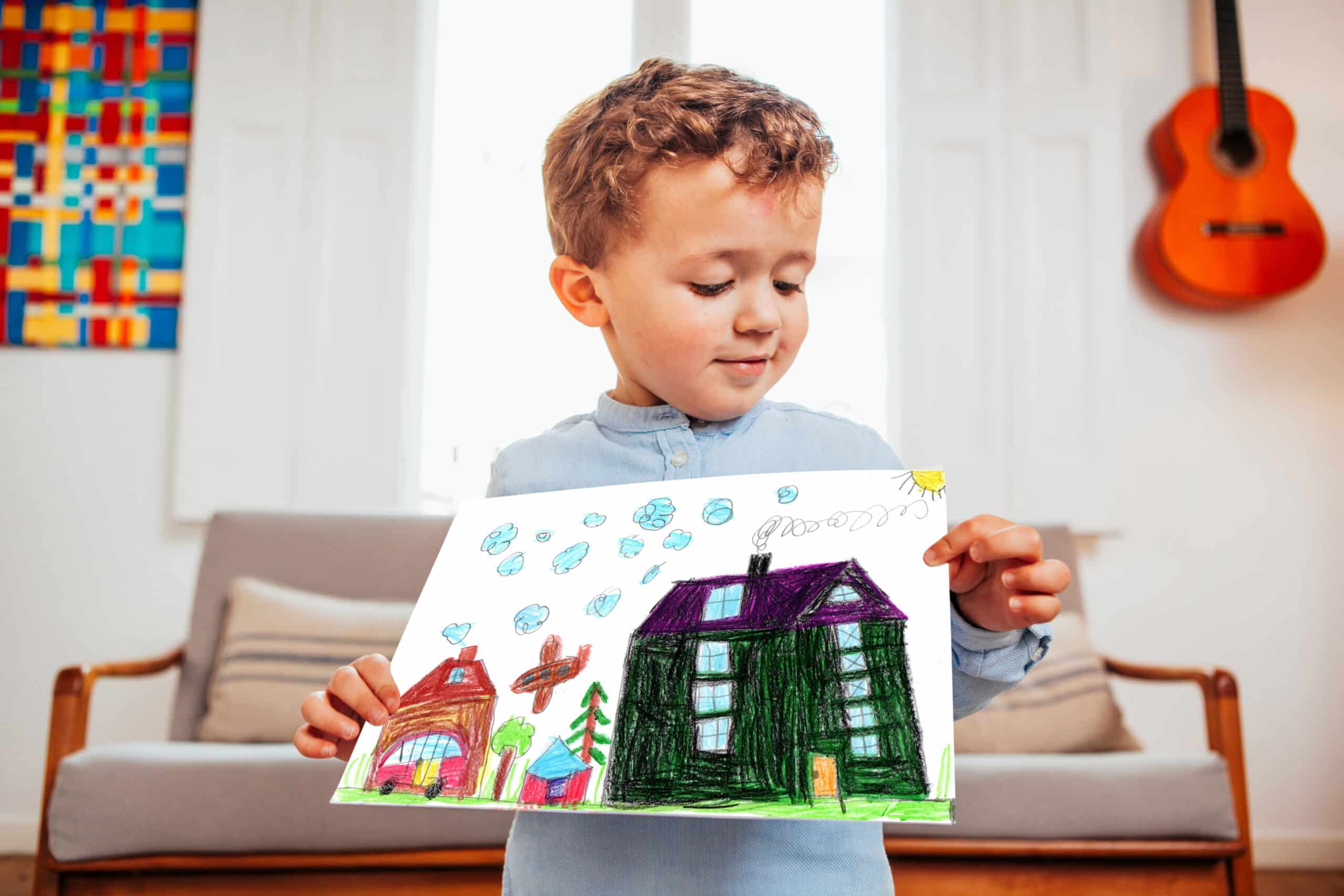 En gutt viser frem en tegning av en bolig.