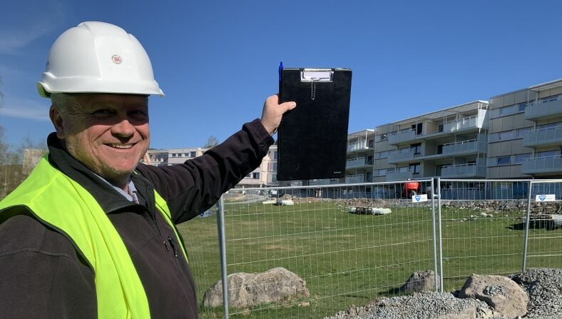 Atle i Prosjektavdelingen i ABBL er på befaring på et rahabiliteringsprosjekt vedrørende innglassering av balkong og peker fornøyd mot fasaden på boligblokka.